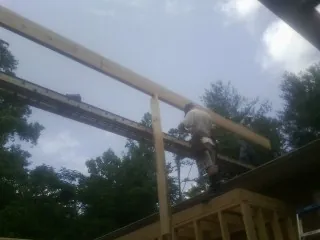 Carpenter setting a ridge beam over a new addition frame — Ice Dam Removal by Roofing Brothers in Brandamore