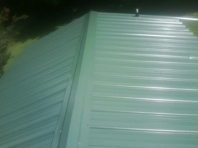 New green metal panels meeting at the ridge of a roof — Flat Roof Repair work by our crew in Brandamore