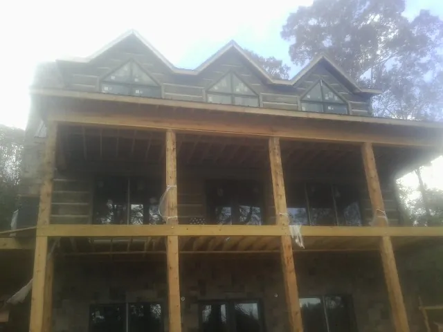 Dormers and porch framing on a large log home under construction — Roof Coating work by our crew in Brandamore