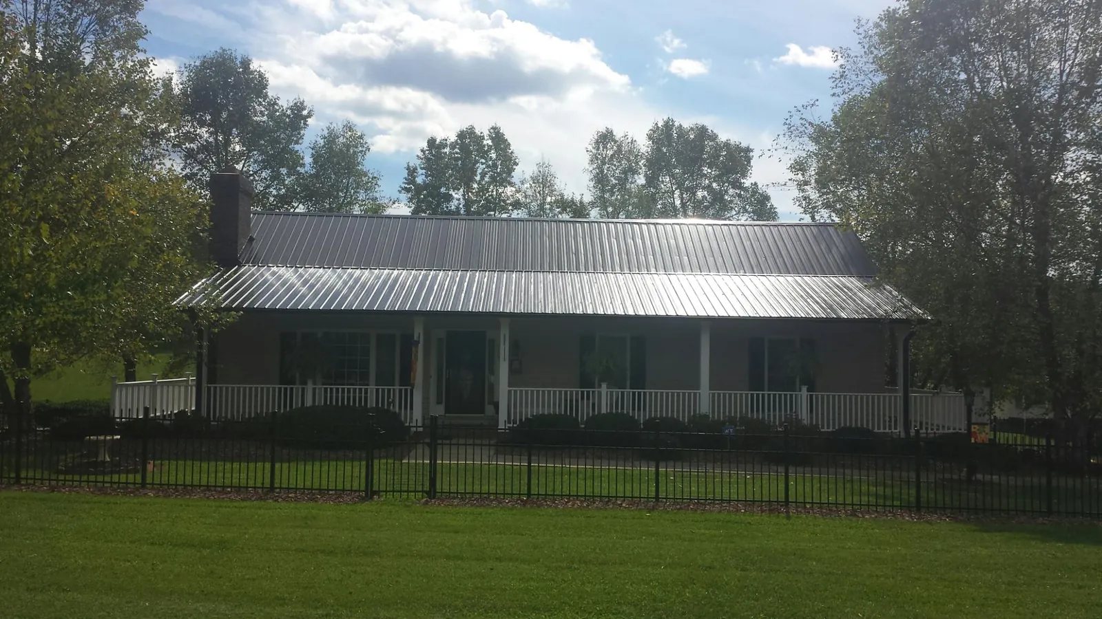 Gray metal roof on a brick ranch with a full width front porch — Gutter Guard Installation work by our crew in Brandamore