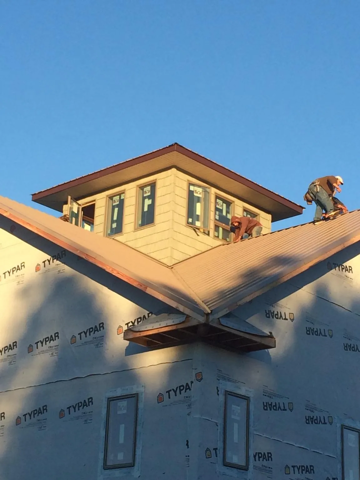 Roofers working around a rooftop cupola on a new metal roof at sunset — Roof Waterproofing in Brandamore by Roofing Brothers